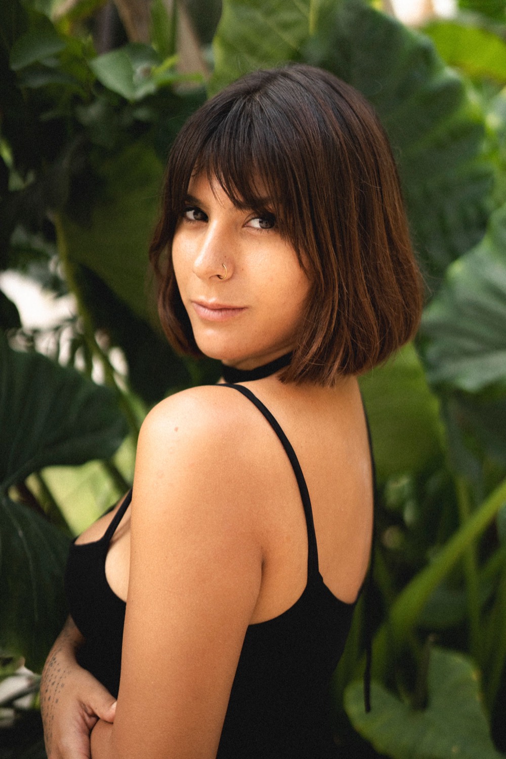 Emanuela looking back over her shoulder among large green leaves